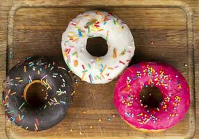 Beautiful sweet food. Stack of glazed colorful assorted donuts on a wooden background. photo