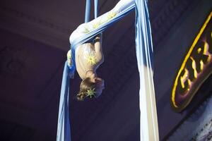 el niña realiza acrobático números en el lienzos un pequeño circo artista realiza en el lienzos de acróbatas. niño realizar acrobático elementos en el aire foto