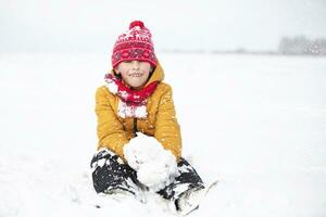 Funny little boy in colorful clothes playing outdoors during a snowfall. Active holidays with children in winter on cold snowy days. Happy child is having fun and playing in winter. photo