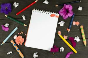 Paper notebook with blank pages, crumpled paper balls and colored pencils on wooden background, creative writing concept. A minimalist workplace for a writer or artist. Creative torment. photo