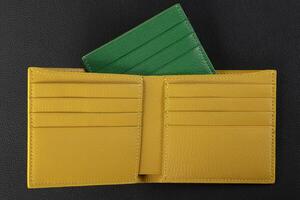 Leather products. Wallet business card holder made of green and yellow genuine leather on a black background. photo