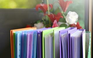 Back view of various plastic file folders for storing important documents in a file box for neatness and easy finding places near transparent glass window, blurred edited background. photo