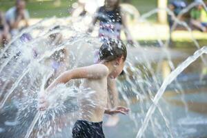 A little boy enjoys the cold waters of a fountain during the heat wave. photo