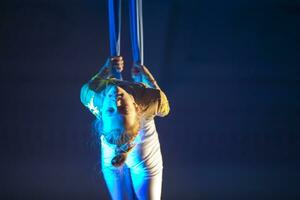 el niña realiza acrobático números en el lienzos un pequeño circo artista realiza en el lienzos de acróbatas. niño realizar acrobático elementos en el aire foto