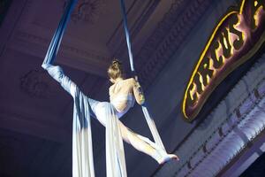 el niña realiza acrobático números en el lienzos un pequeño circo artista realiza en el lienzos de acróbatas. niño realizar acrobático elementos en el aire foto