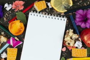 papel cuaderno con blanco páginas, estropeado papel pelotas y lápices de color, dispersado comidas en de madera fondo, creativo Cocinando receta escritura concepto. viniendo arriba y escritura abajo recetas para cocinando. foto