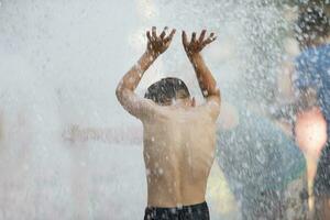 niño en el lluvia. un pequeño chico soportes con su espalda a el cámara en el torrencial lluvia. foto