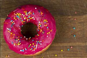 Creative sweet food. Glazed colorful donut on a wooden background. photo