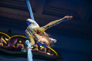 el niña realiza acrobático números en el lienzos un pequeño circo artista realiza en el lienzos de acróbatas. niño realizar acrobático elementos en el aire foto