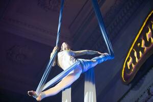 el niña realiza acrobático números en el lienzos un pequeño circo artista realiza en el lienzos de acróbatas. niño realizar acrobático elementos en el aire foto