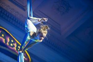 el niña realiza acrobático números en el lienzos un pequeño circo artista realiza en el lienzos de acróbatas. niño realizar acrobático elementos en el aire foto