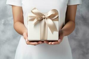A white gift box is in the hands of a woman in a white dress. Gift with a beautiful ribbon. Holidays concept. Generative AI photo