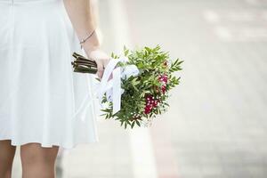 The bride's hand is casually holding a wedding bouquet. photo