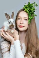 Portrait of a rural girl with a bunch of parsley on her head and a rabbit. photo