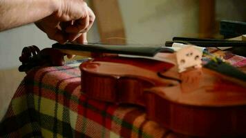 Luthier placing the strings to a violin or viola in the workplace video