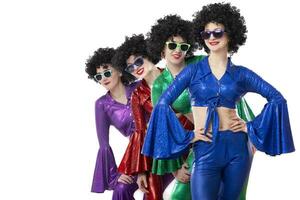 A group of girls in disco style and African wigs in colorful costumes on a white background. photo