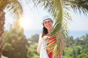 Beautiful middle-aged woman on a summer vacation against the backdrop of tropical palms. photo