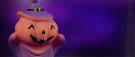 Halloween pumpkin witch doll on purple background. photo