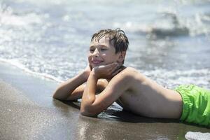 Happy boy is resting by the sea, enjoying the waves and summer vacation. Child on vacation at the seaside. photo