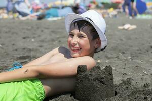 contento chico mentiras en el playa con negro magnético arena. foto