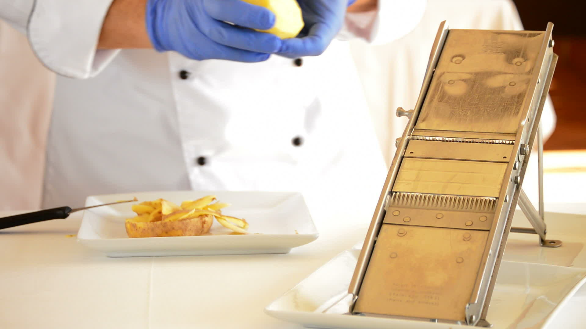 Professional chef hands cutting potatoes with knife and mandolin