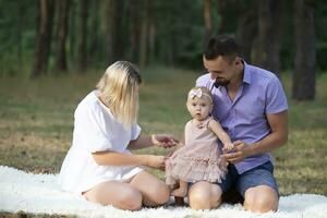 Husband, wife and their little daughter for a walk in the park. Portrait of a young European family in the forest. photo