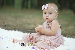 A beautiful little girl on a walk in a summer park. One year old child. Sweet baby. photo