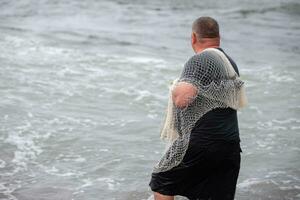 un pescador con un pescar red entra el mar. foto