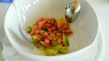 Professional chef hands mixing tomato avocado and other ingredients in a bowl video