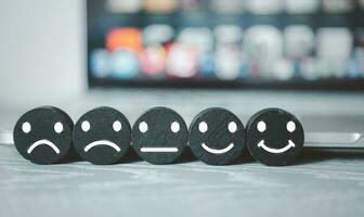 Black wood block with face icon to give satisfaction placed in service in front of the computer. photo