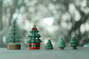 A row of various sizes of miniature toy Christmas trees on a blurred natural green background. photo