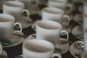 muchos vacío tazas con cucharas para Servicio café en seminario evento o reunión habitación foto