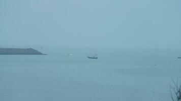 The peaceful sea view with the fishing boat sailing on it in the cloudy day photo