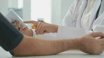 Female doctor checking old woman blood pressure at clinic and filling patient history in the morning. video