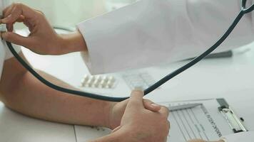 Close-up of a hand of a female doctor using a stethoscope to checking lung for a middle-aged patient who has a fever and comes to see the doctor at the health care center. video