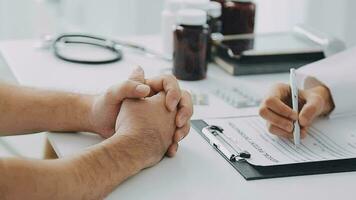 Doctor reassuring patient sitting and discussing something near each other at the white desk in clinic, close up. Empathy in medicine concept video