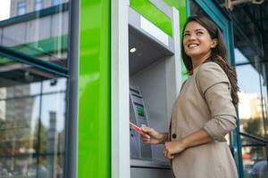 mujer retirarse efectivo a un Cajero automático. joven mujer retirarse dinero desde crédito tarjeta a Cajero automático foto