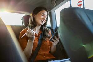 Beautiful Businesswoman is Commuting from Office in a Backseat of Her Car. Entrepreneur Using Smartphone while in Transfer Taxi in Urban City Street photo