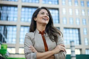 Business woman looking sideways while waiting for a cab in the morning. Happy young woman in the city. photo