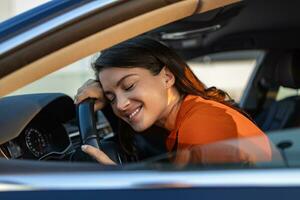 Young Woman Embracing Her New Car. Excited young woman and her new car indoors. Young and cheerful woman enjoying new car hugging steering wheel sitting inside photo