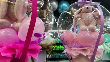 transparent cadeau boîte avec coloré des ballons et doux jouet lapins à l'intérieur pour anniversaire et autre vacances événements dans cadeau et décoration magasin. cadeau gros boîte avec une jouet dans une boutique. video