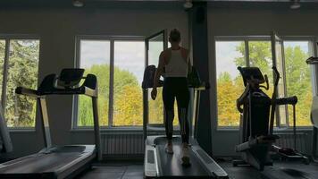 A young slender woman works out on a treadmill in the gym of a modern fitness center video