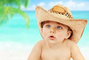 bebé chico en vaquero sombrero en playa foto