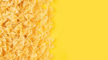 Scattered raw pasta farfalle isolated on yellow background. Food background, italian cuisine photo