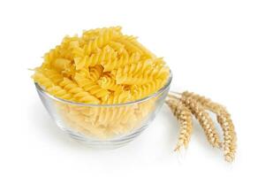 Raw pasta fusilli in bowl and wheat spikelets isolated on white background photo
