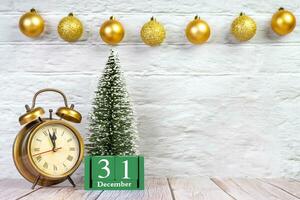 Decorative Christmas tree, green perpetual calendar and alarm clock on white wooden background. photo