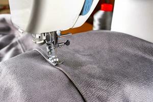 máquina de coser moderna y tela gris. proceso de costura, hecho a mano, hobby, bricolaje, negocio, reparación foto