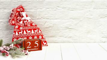 Red gift bag, Christmas tree and red perpetual wooden calendar on white brick background. photo