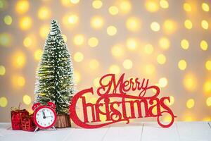 Christmas tree, golden balls and red wooden lettering Merry Christmas on light bokeh background. photo