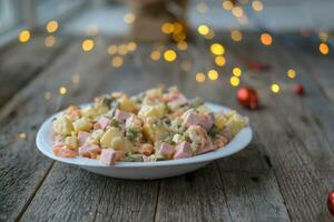 Homemade New Year is Olivier salad on a wooden background. A plate of traditional Russian Christmas salad. photo